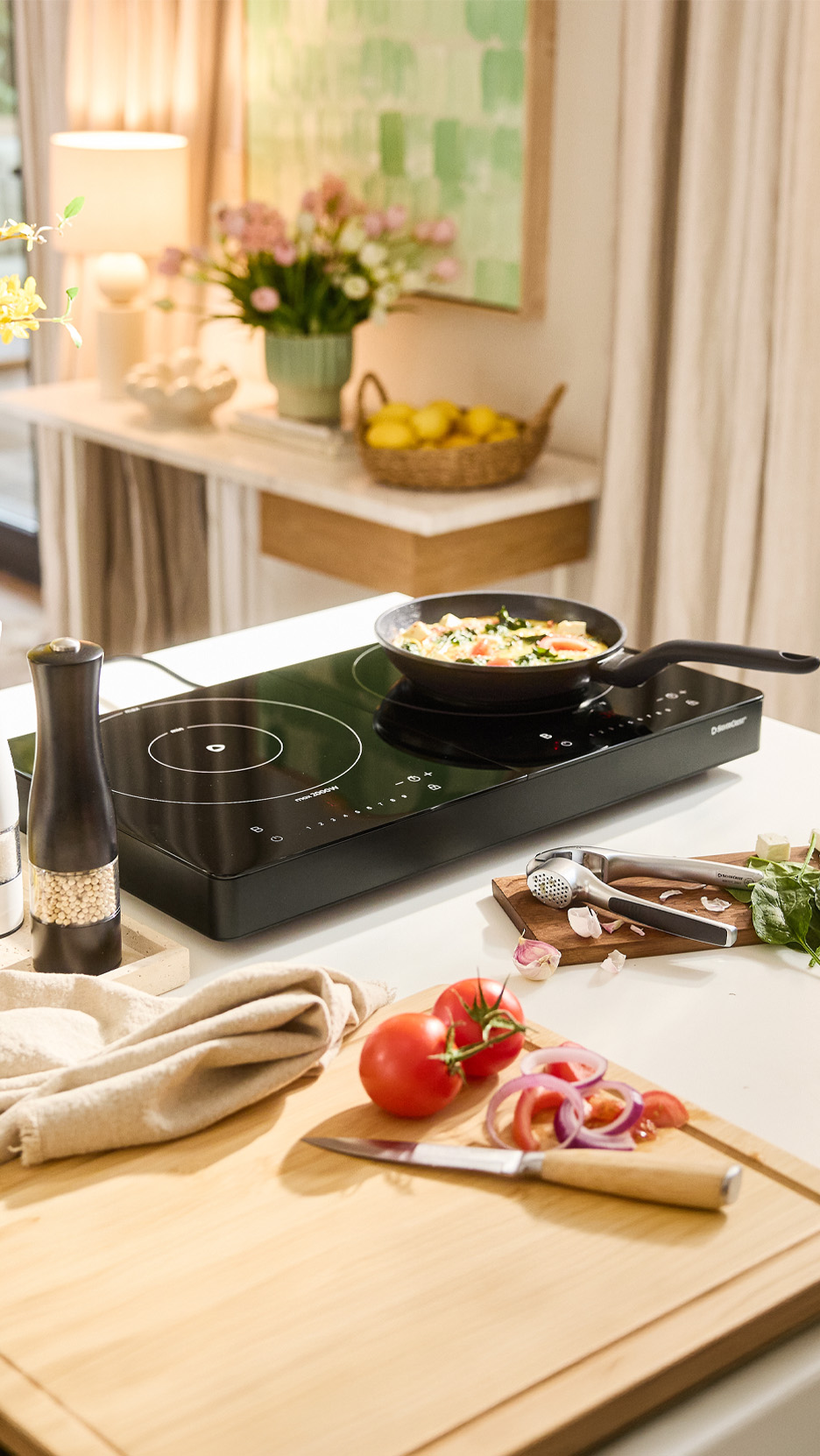 Plită cu inducție portabilă cu o tigaie de gătit, legume proaspete și ustensile de bucătărie.