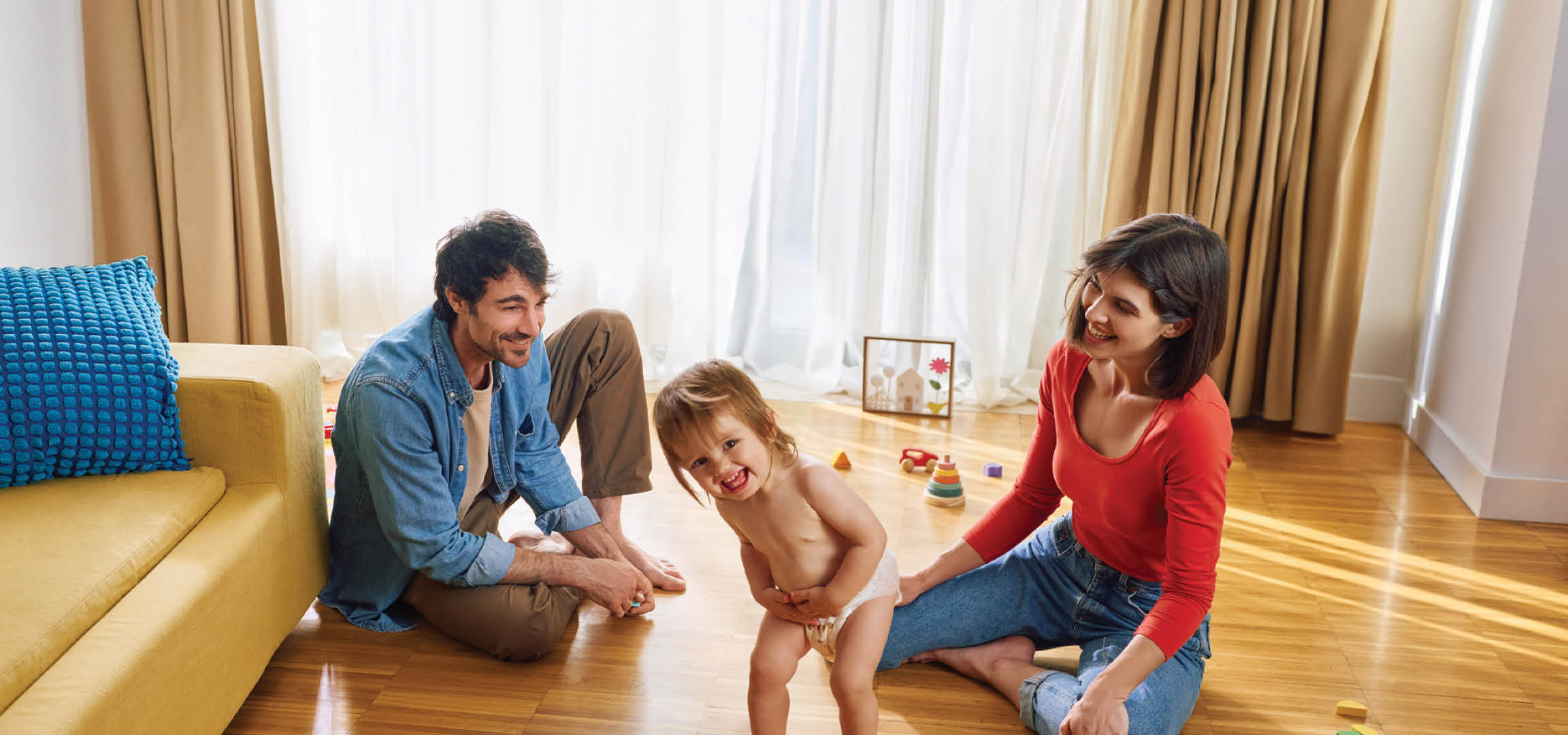 O cuplu tânăr se joacă pe podea cu copilul lor.