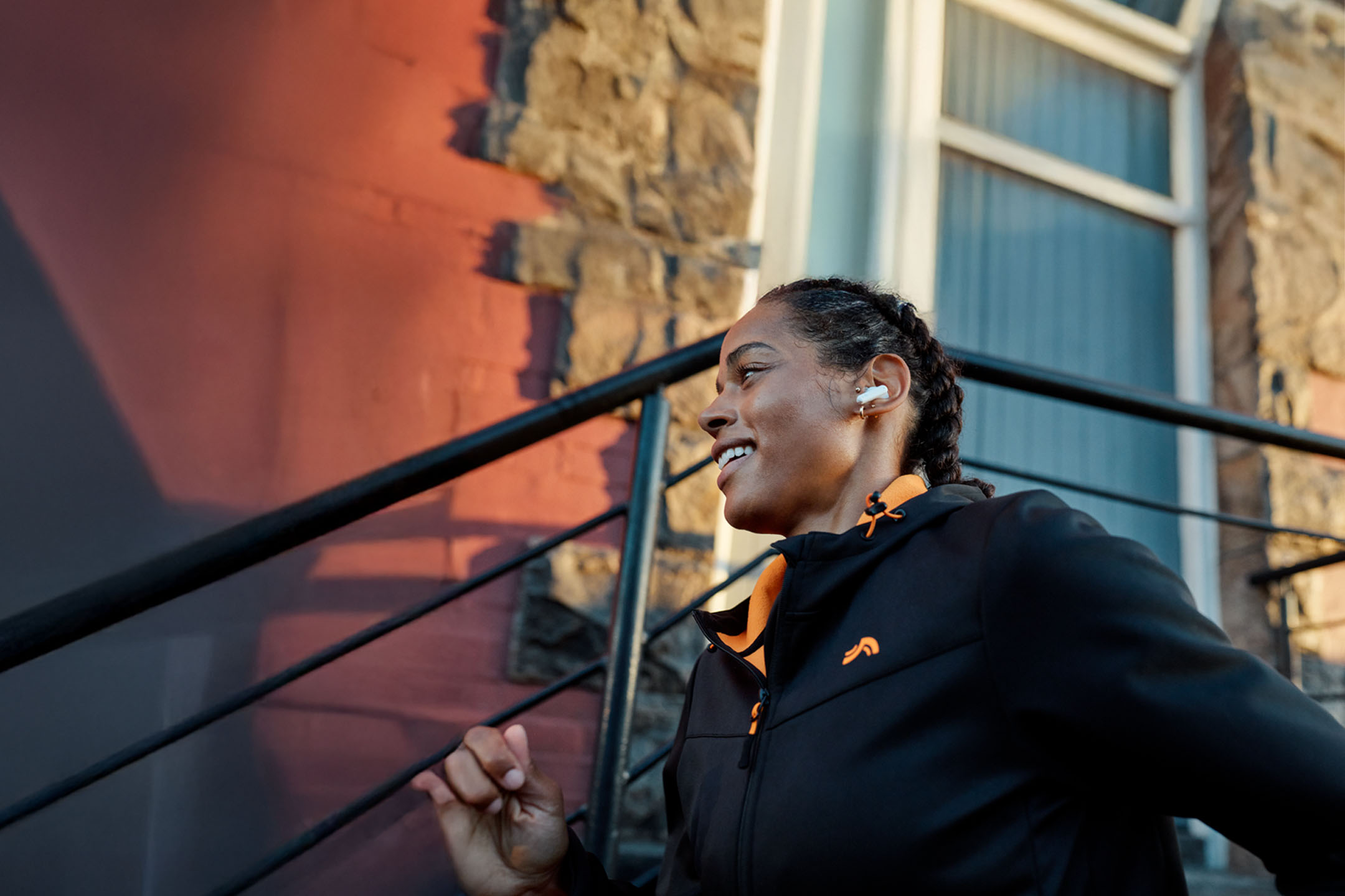 Femeie alergând cu căști, purtând o geacă.