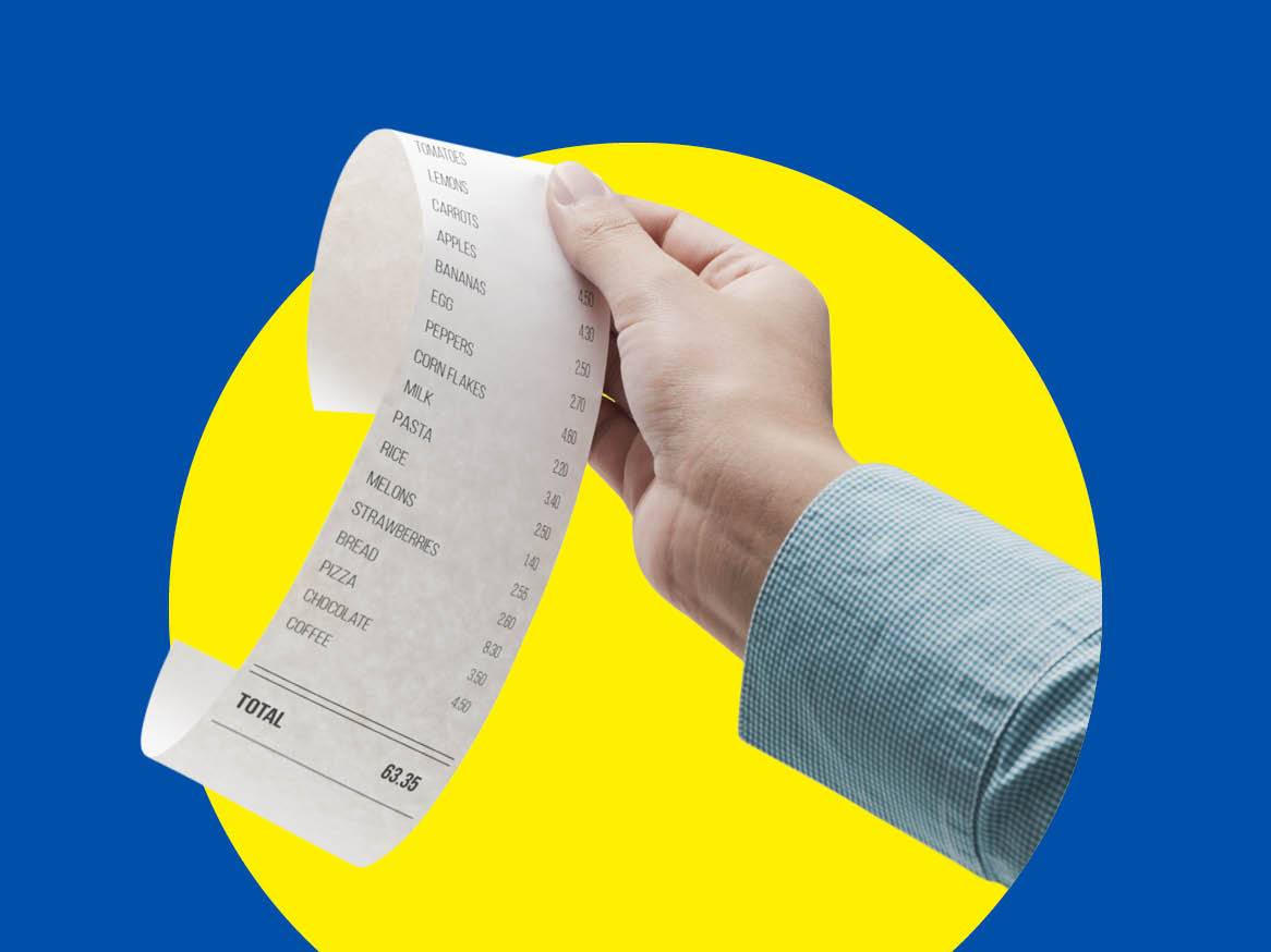 O mână ține o chitanță de cumpărături cu articole precum roșii, lămâi, morcovi și un total de 63,35.